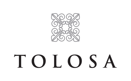 TOLOSA logo: ornamental gray emblem above the word TOLOSA in bold serif letters.